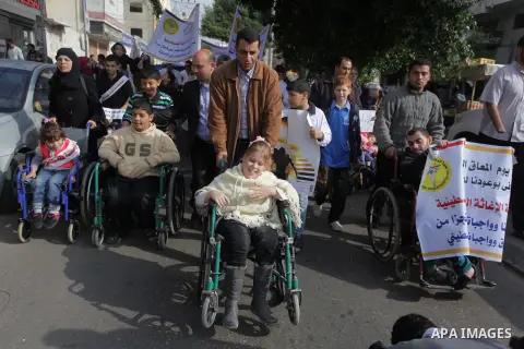 Palestinians and physically challenged people take part in a rally marking the International Day of Persons with Disabilities in Gaza City on Dec. 04, 2013. According to a United Nations report on disabilities, physical,...