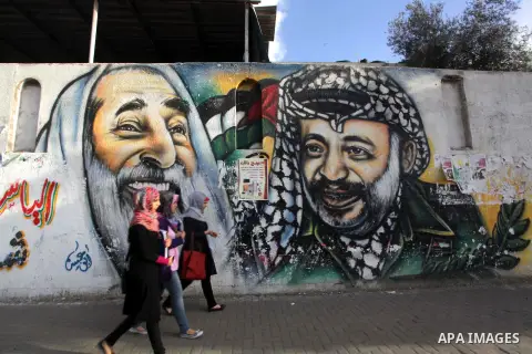 Palestinians walk pass a mural shows the late Palestinian leader Yasser Arafat, in Gaza City on Dec. 04, 2013 . Media reports on 03 December 2013 state that late Palestinian leader Yasser Arafat did not die of poisoning...