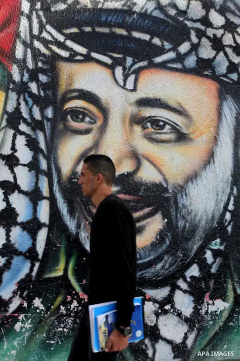 A Palestinian man walks pass a mural shows the late Palestinian leader Yasser Arafat, in Gaza City on Dec. 04, 2013 . Media reports on 03 December 2013 state that late Palestinian leader Yasser Arafat did not die of pois...