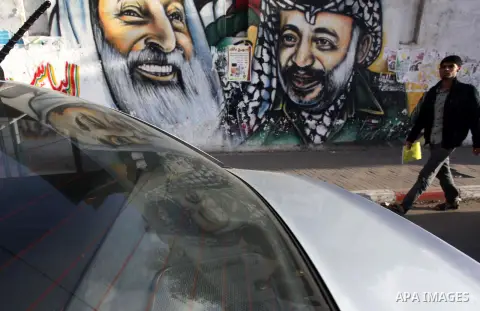 A Palestinian man walks pass a mural shows the late Palestinian leader Yasser Arafat, in Gaza City on Dec. 04, 2013 . Media reports on 03 December 2013 state that late Palestinian leader Yasser Arafat did not die of pois...
