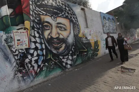 Palestinians walk pass a mural shows the late Palestinian leader Yasser Arafat, in Gaza City on Dec. 04, 2013 . Media reports on 03 December 2013 state that late Palestinian leader Yasser Arafat did not die of poisoning...
