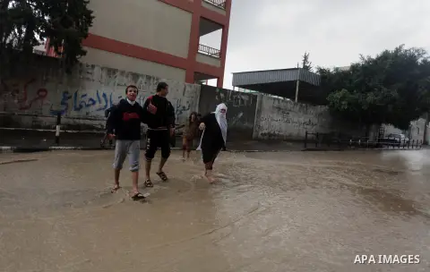 Palestinians walk past in a flooded street after a torrential rains in Gaza city, on Dec. 05, 2013. Photo by Ashraf Amra