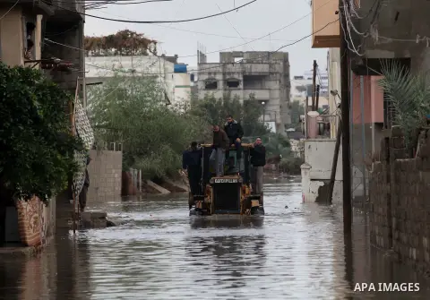 Palestinian civil defense arrive on a boat to help a Palestinian man after his car was submerged in a flooded street following heavy rainfall in Gaza City on December 5, 2013. Photo by Ashraf Amra