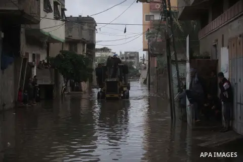 Palestinian civil defense arrive on a boat to help a Palestinian man after his car was submerged in a flooded street following heavy rainfall in Gaza City on December 5, 2013. Photo by Ashraf Amra