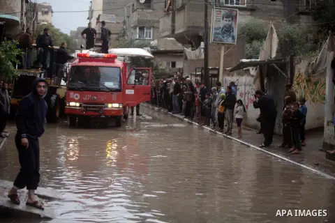 Palestinian civil defense arrive on a boat to help a Palestinian man after his car was submerged in a flooded street following heavy rainfall in Gaza City on December 5, 2013. Photo by Ashraf Amra