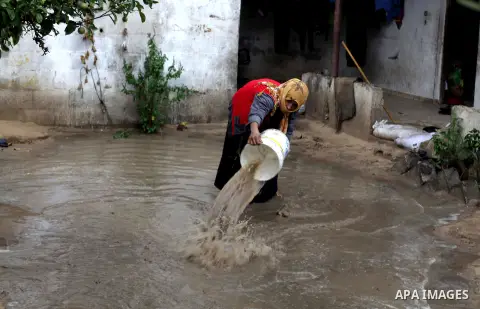 A Palestinian woman trying to take water outside her home during a rainy and cold day in Gaza city, on Dec. 05, 2013. Photo by Ashraf Amra