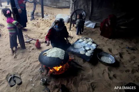 A Palestinian woman bakes bread on firewood during a rainy and cool day in Gaza city, on Dec. 05, 2013. Photo by Ashraf Amra