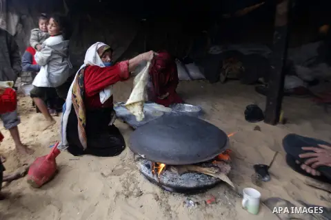 A Palestinian woman bakes bread on firewood during a rainy and cool day in Gaza city, on Dec. 05, 2013. Photo by Ashraf Amra
