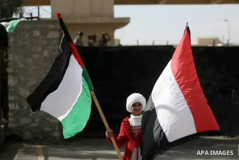 A Palestinian sick girl holds flags at the gate of the Rafah border crossing point, on December 5, 2013, as Egyptian soldiers look on during a demonstration held by Palestinian doctors and patients demanding the permanen...