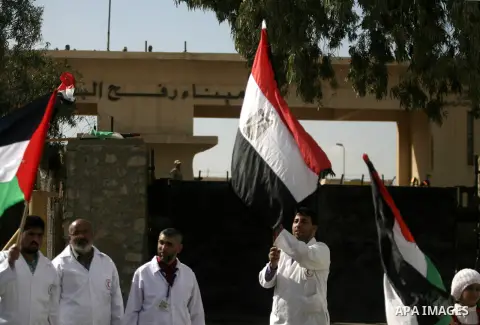 Palestinian doctors and patients hold flags at the gate of the Rafah border crossing point, on December 5, 2013, as Egyptian soldiers look on during a demonstration held by Palestinian doctors and patients demanding the...