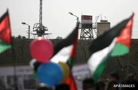 Palestinian doctors and patients hold placards and ballons at the gate of the Rafah border crossing point, on December 5, 2013, as Egyptian soldiers look on during a demonstration held by Palestinian doctors and patients...