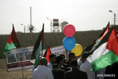 Palestinian doctors and patients hold placards and ballons at the gate of the Rafah border crossing point, on December 5, 2013, as Egyptian soldiers look on during a demonstration held by Palestinian doctors and patients...
