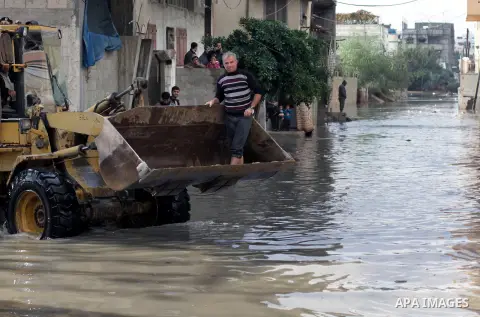 Palestinians ride a bulldozer in a flooded street following heavy rainfall in Gaza City on December 5, 2013. Photo by Ashraf Amra