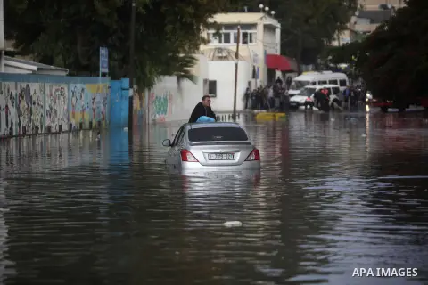 A Palestinian man waits for help after his cas was submerged in a flooded street following heavy rainfall in Gaza City on December 5, 2013. Photo by Ashraf Amra