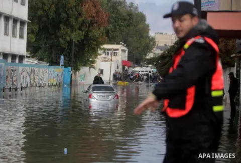 Palestinian civil defence try to remove a car submerged in a flooded street following heavy rainfall in Gaza City on December 5, 2013. Photo by Ashraf Amra