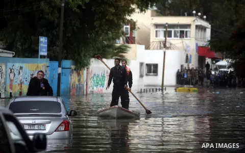Palestinian civil defense arrive on a boat to help a Palestinian man after his car was submerged in a flooded street following heavy rainfall in Gaza City on December 5, 2013. Photo by Ashraf Amra