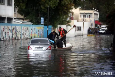 Palestinian civil defence help a man after his cas was submerged in a flooded street following heavy rainfall in Gaza City on December 5, 2013. Photo by Ashraf Amra