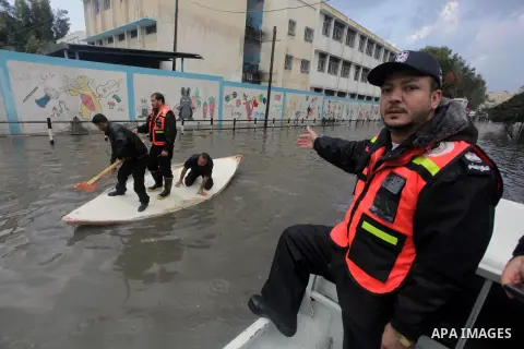 Palestinian civil defense arrive on a boat to help a Palestinian man after his car was submerged in a flooded street following heavy rainfall in Gaza City on December 5, 2013. Photo by Ashraf Amra