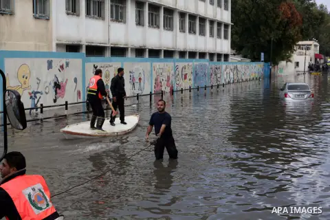 Palestinian civil defense arrive on a boat to help a Palestinian man after his car was submerged in a flooded street following heavy rainfall in Gaza City on December 5, 2013. Photo by Ashraf Amra