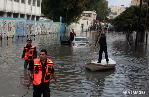 Palestinian civil defense arrive on a boat to help a Palestinian man after his car was submerged in a flooded street following heavy rainfall in Gaza City on December 5, 2013. Photo by Ashraf Amra
