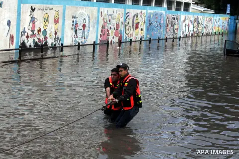Palestinian civil defence try to remove a car submerged in a flooded street following heavy rainfall in Gaza City on December 5, 2013. Photo by Ashraf Amra