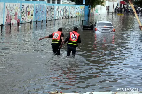 Palestinian civil defence try to remove a car submerged in a flooded street following heavy rainfall in Gaza City on December 5, 2013. Photo by Ashraf Amra