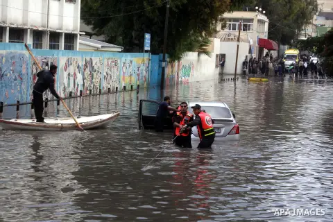 Palestinian civil defence try to remove a car submerged in a flooded street following heavy rainfall in Gaza City on December 5, 2013. Photo by Ashraf Amra