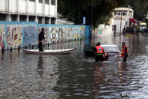 Palestinian civil defence try to remove a car submerged in a flooded street following heavy rainfall in Gaza City on December 5, 2013. Photo by Ashraf Amra