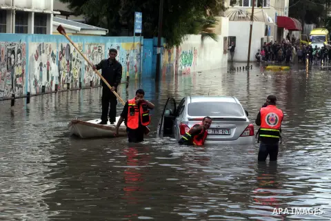 Palestinian civil defence try to remove a car submerged in a flooded street following heavy rainfall in Gaza City on December 5, 2013. Photo by Ashraf Amra