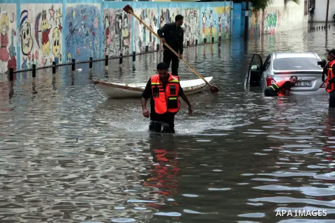 Palestinian civil defence try to remove a car submerged in a flooded street following heavy rainfall in Gaza City on December 5, 2013. Photo by Ashraf Amra