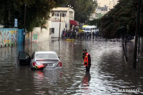Palestinian civil defence try to remove a car submerged in a flooded street following heavy rainfall in Gaza City on December 5, 2013. Photo by Ashraf Amra