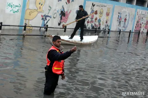 Palestinian civil defense arrive on a boat to help a Palestinian man after his car was submerged in a flooded street following heavy rainfall in Gaza City on December 5, 2013. Photo by Ashraf Amra