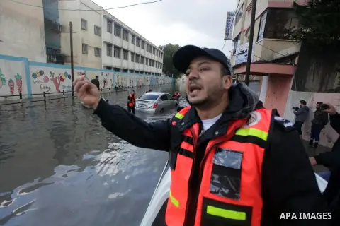 Palestinian civil defence try to remove a car submerged in a flooded street following heavy rainfall in Gaza City on December 5, 2013. Photo by Ashraf Amra