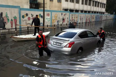 Palestinian civil defense arrive on a boat to help a Palestinian man after his car was submerged in a flooded street following heavy rainfall in Gaza City on December 5, 2013. Photo by Ashraf Amra