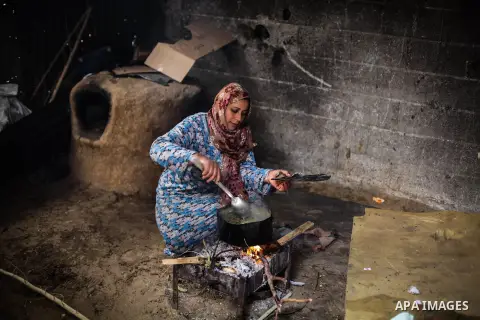 A Palestinian woman cooks on firewood in her house during a heavy raining day in Beit Lahiya, northern Gaza Strip, Thursday, Dec. 5, 2013. Heavy rains flooded most streets and blocked some of the streets of the refugee c...