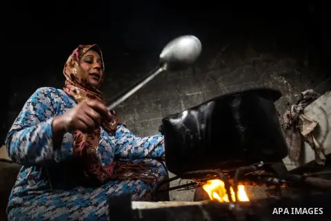 A Palestinian woman cooks on firewood in her house during a heavy raining day in Beit Lahiya, northern Gaza Strip, Thursday, Dec. 5, 2013. Heavy rains flooded most streets and blocked some of the streets of the refugee c...