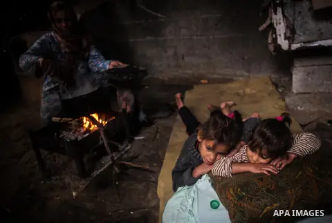Palestinian children sleep as their mother cooks on firewood in their house during a heavy raining day in Beit Lahiya, northern Gaza Strip, Thursday, Dec. 5, 2013. Heavy rains flooded most streets and blocked some of the...