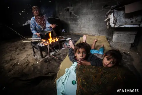 Palestinian children pose as their mother cooks on firewood in their house during a heavy raining day in Beit Lahiya, northern Gaza Strip, Thursday, Dec. 5, 2013. Heavy rains flooded most streets and blocked some of the...