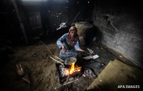 A Palestinian woman cooks on firewood in her house during a heavy raining day in Beit Lahiya, northern Gaza Strip, Thursday, Dec. 5, 2013. Heavy rains flooded most streets and blocked some of the streets of the refugee c...
