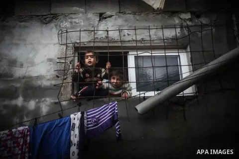 Palestinian children look through a window in their house during a heavy raining day in Beit Lahiya, northern Gaza Strip, Thursday, Dec. 5, 2013. Heavy rains flooded most streets and blocked some of the streets of the re...