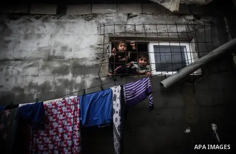 Palestinian children look through a window in their house during a heavy raining day in Beit Lahiya, northern Gaza Strip, Thursday, Dec. 5, 2013. Heavy rains flooded most streets and blocked some of the streets of the re...