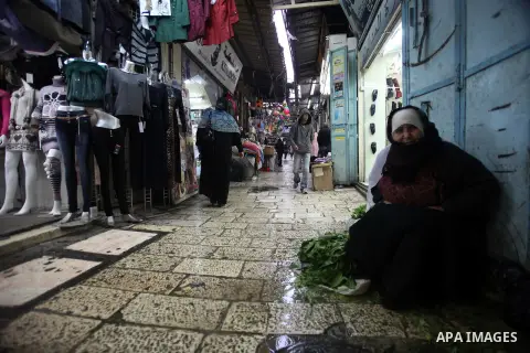 A Palestinian woman sells greens during a rainy day, at a market in Jerusalem's Old City, Dec. 05, 2013. Photo by Saeed Qaq