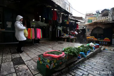 Palestinians walk at a market during a rainy day, in Jerusalem's Old City, Dec. 05, 2013. Photo by Saeed Qaq