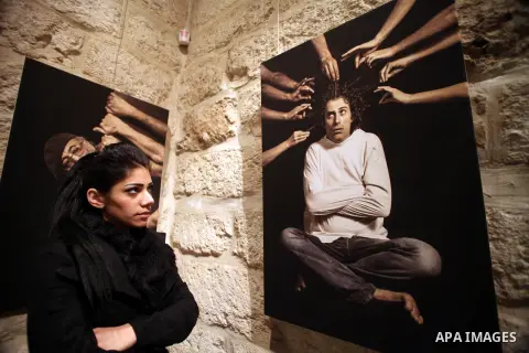 A Palestinian girl looks at a photo during a photogallery named 'Room Four', organised by French culture center in Jerusalem on Dec. 05, 2013. The photos by the artist Ashraf Dowani displayed in the photogallery and refl...