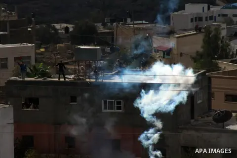 Palestinian protesters take cover from tear gas fired by Israeli security forces as clashes broke out during a demonstration against the expropriation of Palestinian land by Israel in the village of Kfar Qaddum, near the...