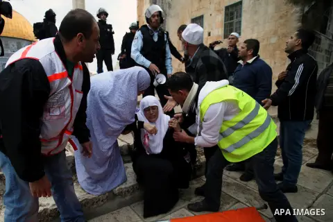 Palestinian medics treat a Palestinian woman injured during clashes between Israeli riot police and stone-throwers following Friday prayers at Jerusalem's al-Aqsa mosque compound, on December 6, 2013. Israeli police hurl...