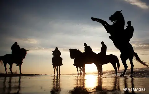 Palestinians ride horses during the sunset on the beach of Gaza City, Dec. 06, 2013. British human rights organization Amnesty International condemned the Israeli blockade on the Gaza Strip in a statement released on Mon...