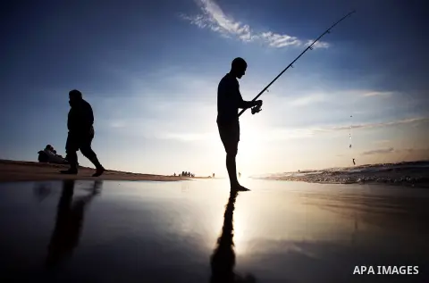 A Palestinian man fishing during the sunset on the beach of Gaza City, Dec. 06, 2013. British human rights organization Amnesty International condemned the Israeli blockade on the Gaza Strip in a statement released on Mo...