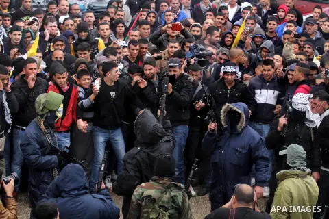 An armed Palestinian man prepares to fire into the air during the funeral of 15-year-old Palestinian Waji al-Ramhi in the Jelazoun refugee camp in the West Bank city of Ramallah on December 8, 2013. Israeli troops shot d...