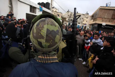 An armed Palestinian man prepares to fire into the air during the funeral of 15-year-old Palestinian Waji al-Ramhi in the Jelazoun refugee camp in the West Bank city of Ramallah on December 8, 2013. Israeli troops shot d...